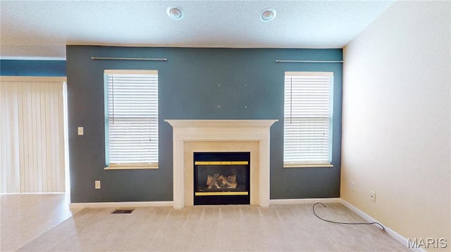 unfurnished living room with a glass covered fireplace, carpet flooring, and baseboards