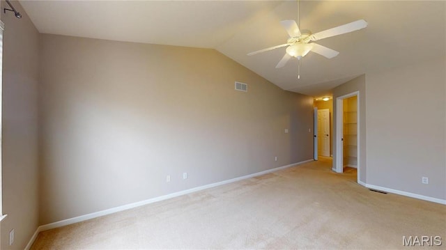 empty room with light colored carpet, vaulted ceiling, ceiling fan, and baseboards