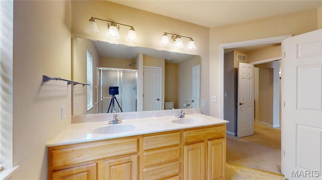 bathroom featuring a stall shower, double vanity, and toilet
