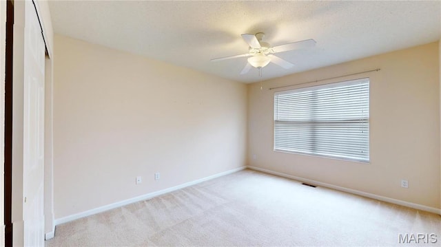 empty room with carpet flooring, baseboards, ceiling fan, and a textured ceiling