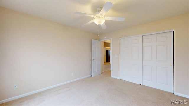unfurnished bedroom with light colored carpet, baseboards, a closet, and a ceiling fan