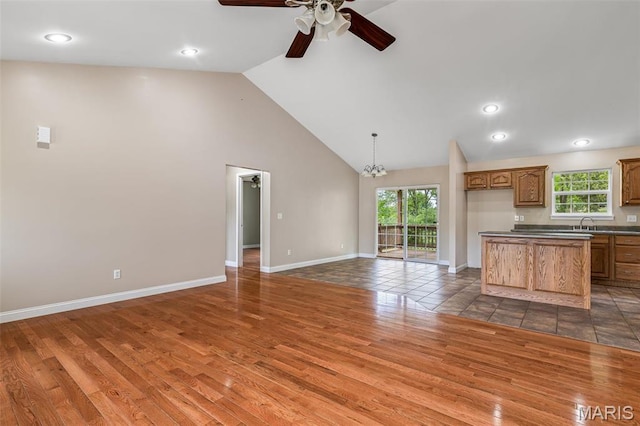 1824 Oak Knl, Farmington, MO 63640 - unfurnished living room with wood finished floors, ceiling fan, high vaulted ceiling, baseboards, and a chandelier