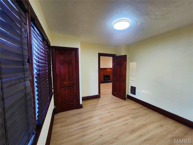 436 Hern Ave, Saint Louis, MO 63135 - unfurnished bedroom with baseboards, light wood-type flooring, a textured ceiling, and a fireplace