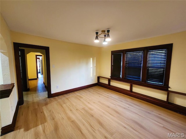 436 Hern Ave, Saint Louis, MO 63135 - unfurnished room with light wood-type flooring, arched walkways, baseboards, and a chandelier