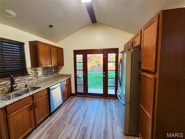 436 Hern Ave, Saint Louis, MO 63135 - kitchen featuring stainless steel appliances, a sink, vaulted ceiling, light wood-style flooring, and decorative backsplash