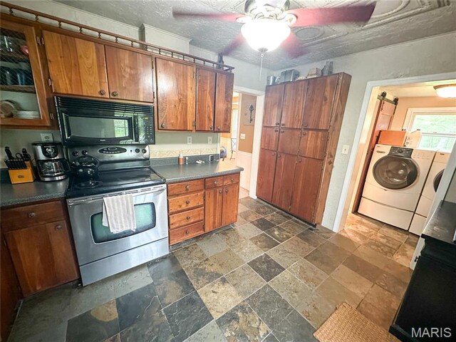 kitchen featuring black microwave, stainless steel electric range, stone tile floors, washer / dryer, and brown cabinetry