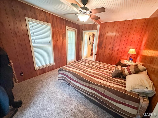 bedroom with carpet floors, wood walls, and ceiling fan