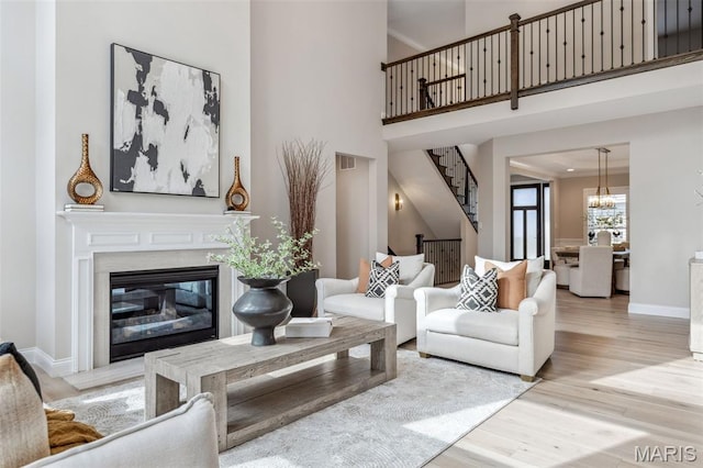 973 Tara Ct, Chesterfield, MO 63005 - living area featuring light wood-style floors, stairs, a premium fireplace, a chandelier, and a towering ceiling