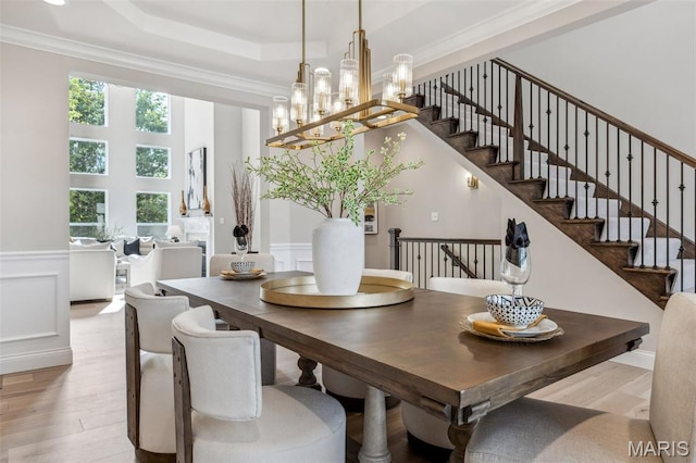 973 Tara Ct, Chesterfield, MO 63005 - dining space featuring light wood-style flooring, stairway, a tray ceiling, ornamental molding, and a wainscoted wall