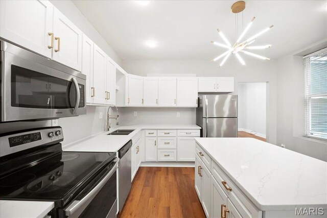 3431 California Ave, Saint Louis, MO 63118 - kitchen with stainless steel appliances, a sink, a chandelier, and white cabinets