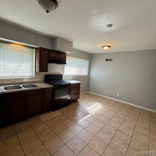 9732 Glen Owen Dr, Saint Louis, MO 63136 - kitchen with black gas stove, a sink, light tile patterned flooring, baseboards, and dark brown cabinets