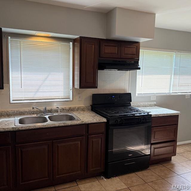 9732 Glen Owen Dr, Saint Louis, MO 63136 - kitchen featuring black gas stove, under cabinet range hood, a sink, light tile patterned flooring, and light countertops