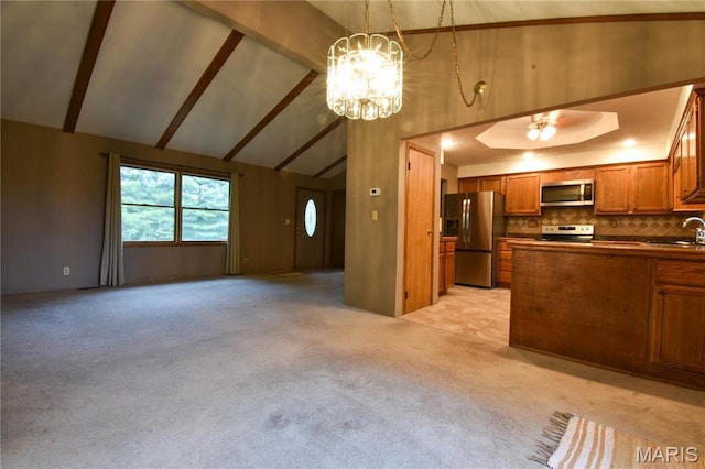 kitchen featuring stainless steel appliances, open floor plan, brown cabinetry, a sink, and high vaulted ceiling