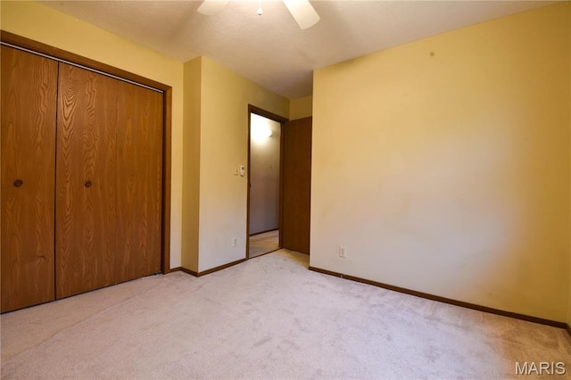 unfurnished bedroom featuring carpet floors, baseboards, a closet, and ceiling fan
