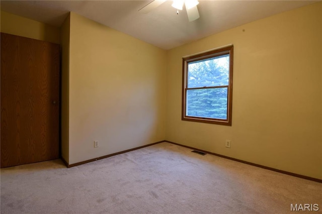 empty room featuring carpet, a ceiling fan, and baseboards