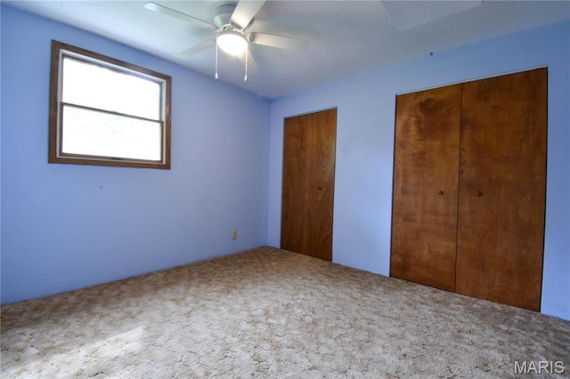 unfurnished bedroom featuring carpet flooring, two closets, and ceiling fan
