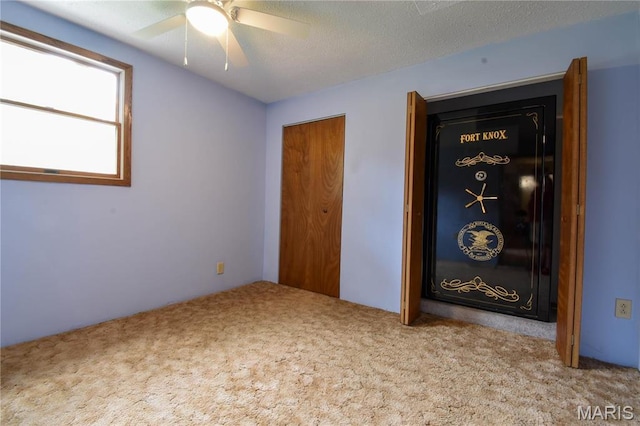 unfurnished bedroom featuring carpet flooring, a textured ceiling, and a ceiling fan