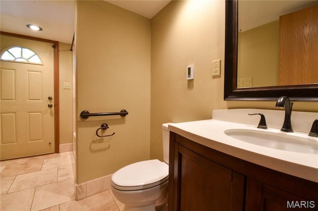 half bath featuring toilet, vanity, baseboards, and tile patterned flooring