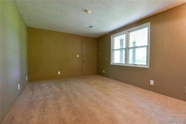 unfurnished room featuring carpet and a textured ceiling