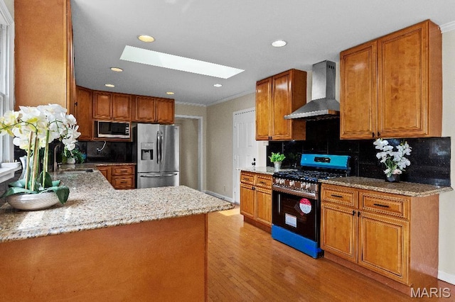 625 Pinebrook Dr, Town And Country, MO 63017 - kitchen with appliances with stainless steel finishes, wall chimney exhaust hood, a skylight, light wood-style floors, and light stone countertops