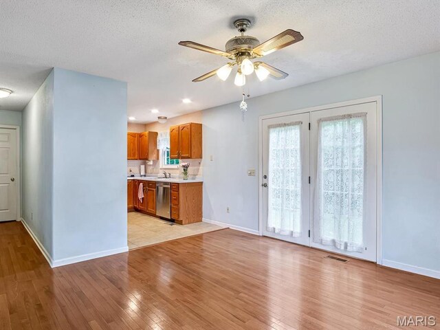 109 Miller Ct, Valmeyer, IL 62295 - kitchen featuring stainless steel dishwasher, light countertops, ceiling fan, brown cabinets, and light wood-style floors
