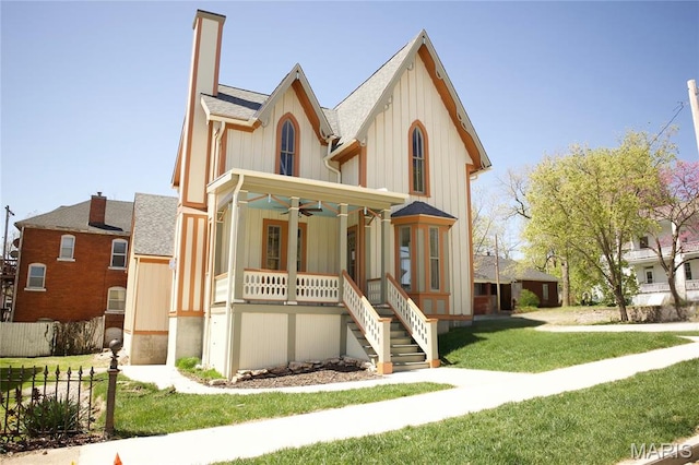 view of front facade with a porch, ceiling fan, a front yard, stairs, and roof with shingles