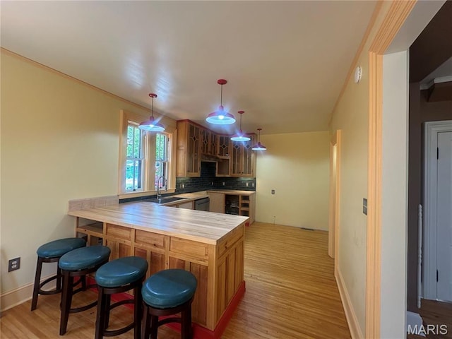 kitchen featuring a peninsula, light wood finished floors, a kitchen breakfast bar, and backsplash