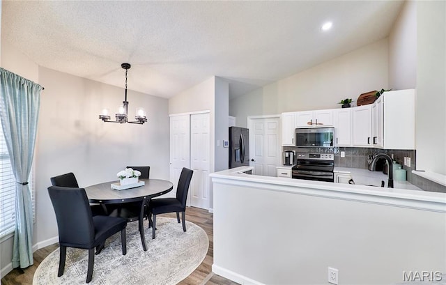 10 Warshire Ct Unit 67B, Ofallon, MO 63366 - kitchen with appliances with stainless steel finishes, a chandelier, wood finished floors, backsplash, and white cabinetry