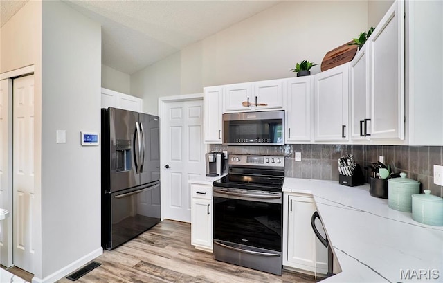 10 Warshire Ct Unit 67B, Ofallon, MO 63366 - kitchen featuring appliances with stainless steel finishes, decorative backsplash, white cabinets, and vaulted ceiling