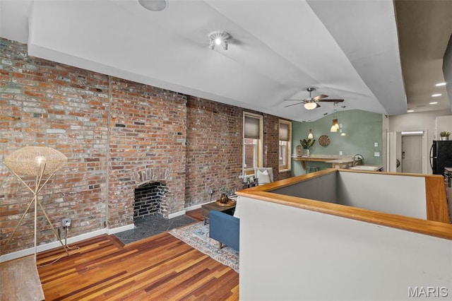 3318 Sidney St, Saint Louis, MO 63104 - living room featuring a ceiling fan, brick wall, wood finished floors, a brick fireplace, and lofted ceiling