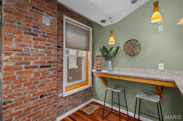 3318 Sidney St, Saint Louis, MO 63104 - dining area featuring wood finished floors, vaulted ceiling, baseboards, and brick wall
