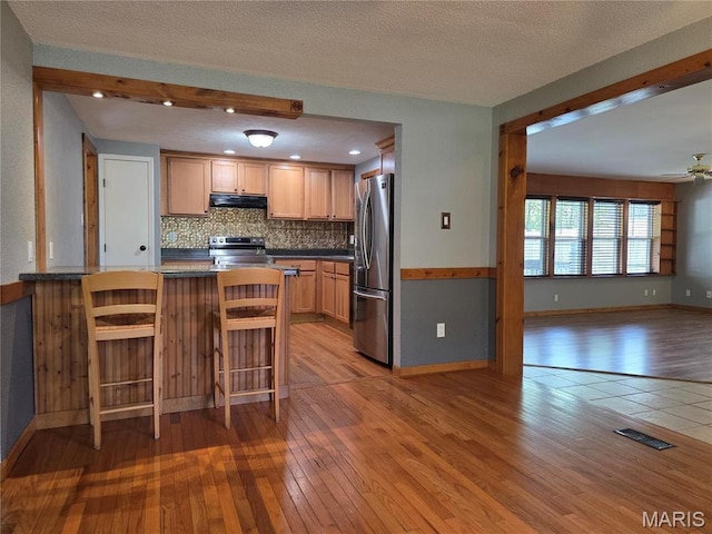 306 Edna Ln, Sparta, IL 62286 - kitchen with stainless steel appliances, ventilation hood, light wood-type flooring, backsplash, and dark countertops