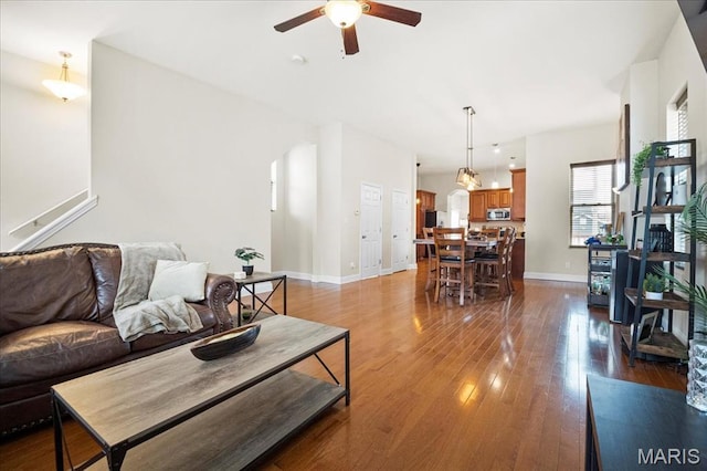 living room with a ceiling fan, baseboards, and wood finished floors