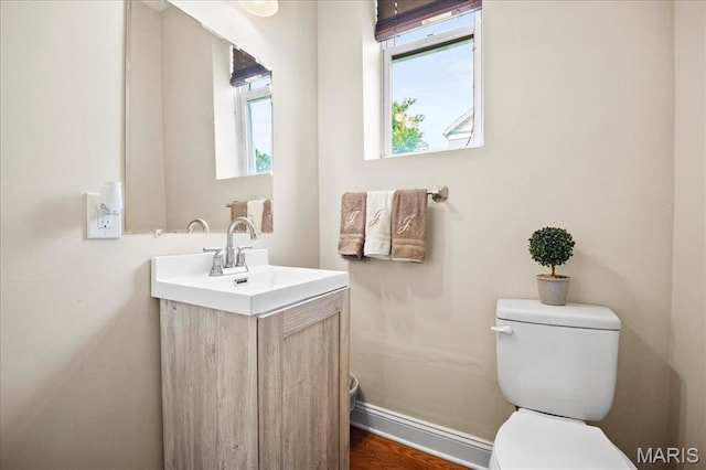 bathroom with toilet, vanity, and baseboards