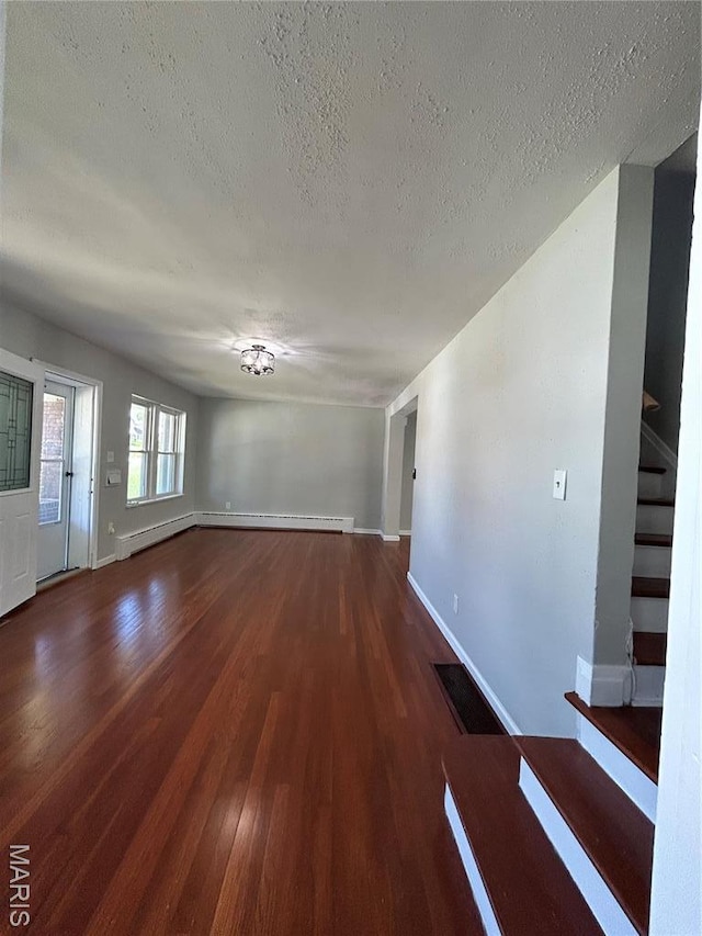 3604 Ridgedale Ave, Saint Louis, MO 63121 - unfurnished living room with a textured ceiling, wood finished floors, stairs, baseboards, and a baseboard heating unit