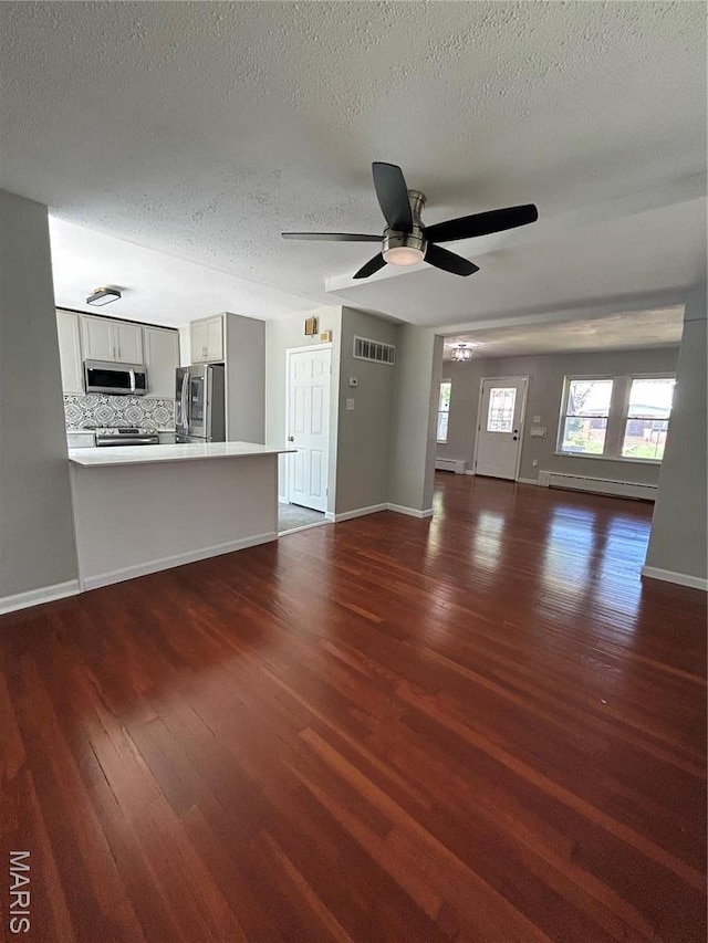 3604 Ridgedale Ave, Saint Louis, MO 63121 - unfurnished living room with dark wood-type flooring, a baseboard radiator, a textured ceiling, a ceiling fan, and baseboards