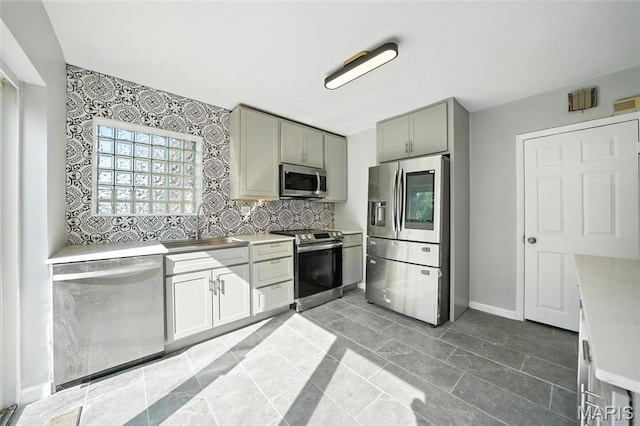 3604 Ridgedale Ave, Saint Louis, MO 63121 - kitchen featuring appliances with stainless steel finishes, light countertops, tasteful backsplash, and gray cabinetry