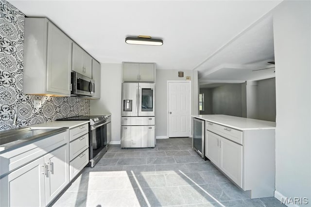 3604 Ridgedale Ave, Saint Louis, MO 63121 - kitchen featuring stainless steel appliances, beverage cooler, light countertops, tasteful backsplash, and gray cabinets