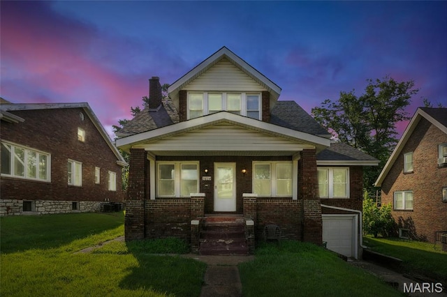 3604 Ridgedale Ave, Saint Louis, MO 63121 - bungalow-style house featuring a garage, a chimney, brick siding, a yard, and covered porch