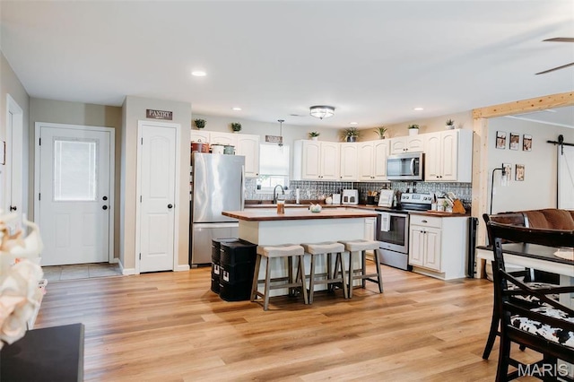 2962 Sherrill Rd, Doe Run, MO 63637 - kitchen featuring stainless steel appliances, tasteful backsplash, white cabinets, a kitchen bar, and recessed lighting