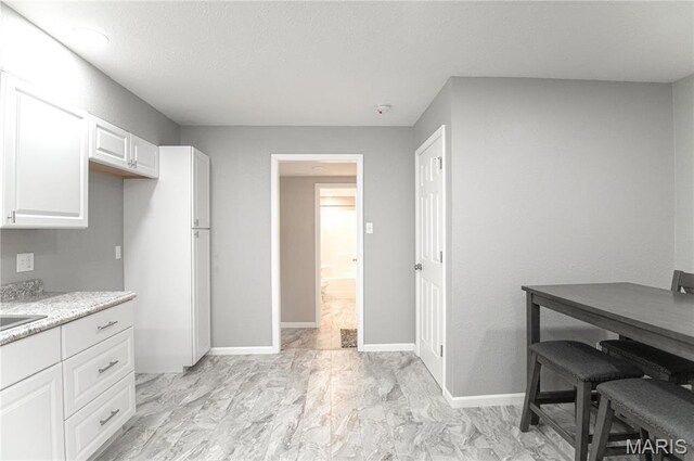 415 W James Blvd, St James, MO 65559 - kitchen featuring white cabinetry, baseboards, and a textured ceiling
