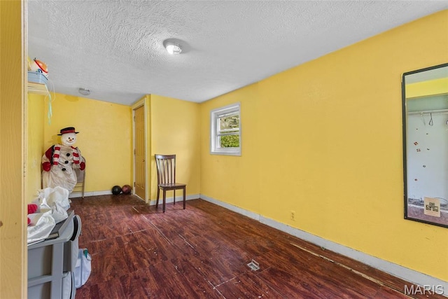 bedroom with wood finished floors, a textured ceiling, and baseboards