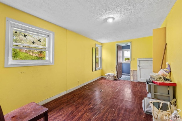 unfurnished room with wood finished floors, a textured ceiling, and baseboards
