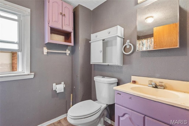 full bath with toilet, vanity, and baseboards