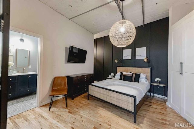 2020 Washington Ave Unit 713, Saint Louis, MO 63103 - bedroom featuring light wood-style flooring, a sink, and ensuite bath