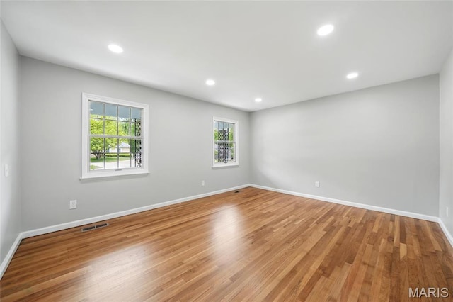 empty room featuring wood finished floors, baseboards, and recessed lighting