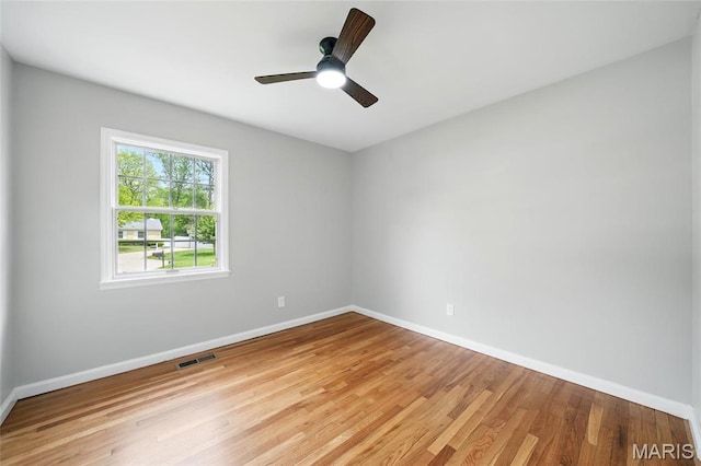 spare room featuring baseboards, light wood finished floors, and a ceiling fan