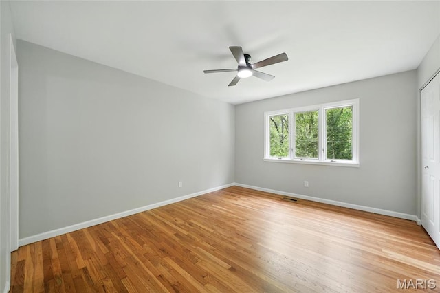 spare room with baseboards, ceiling fan, and light wood finished floors