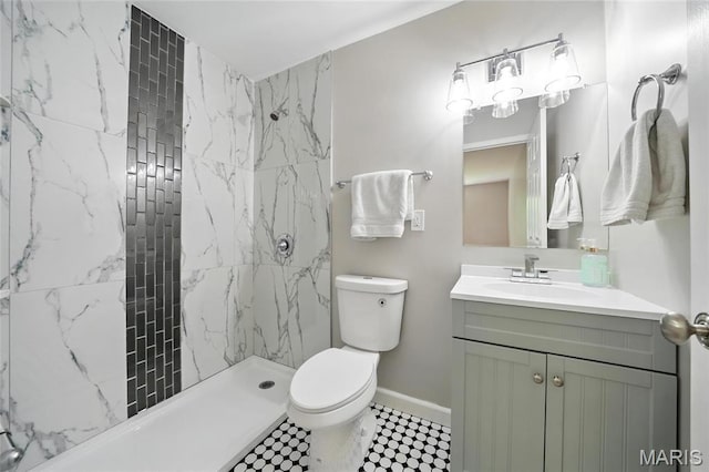 bathroom featuring toilet, vanity, tiled shower, and baseboards