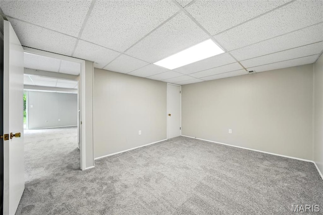 spare room featuring carpet, a paneled ceiling, and baseboards